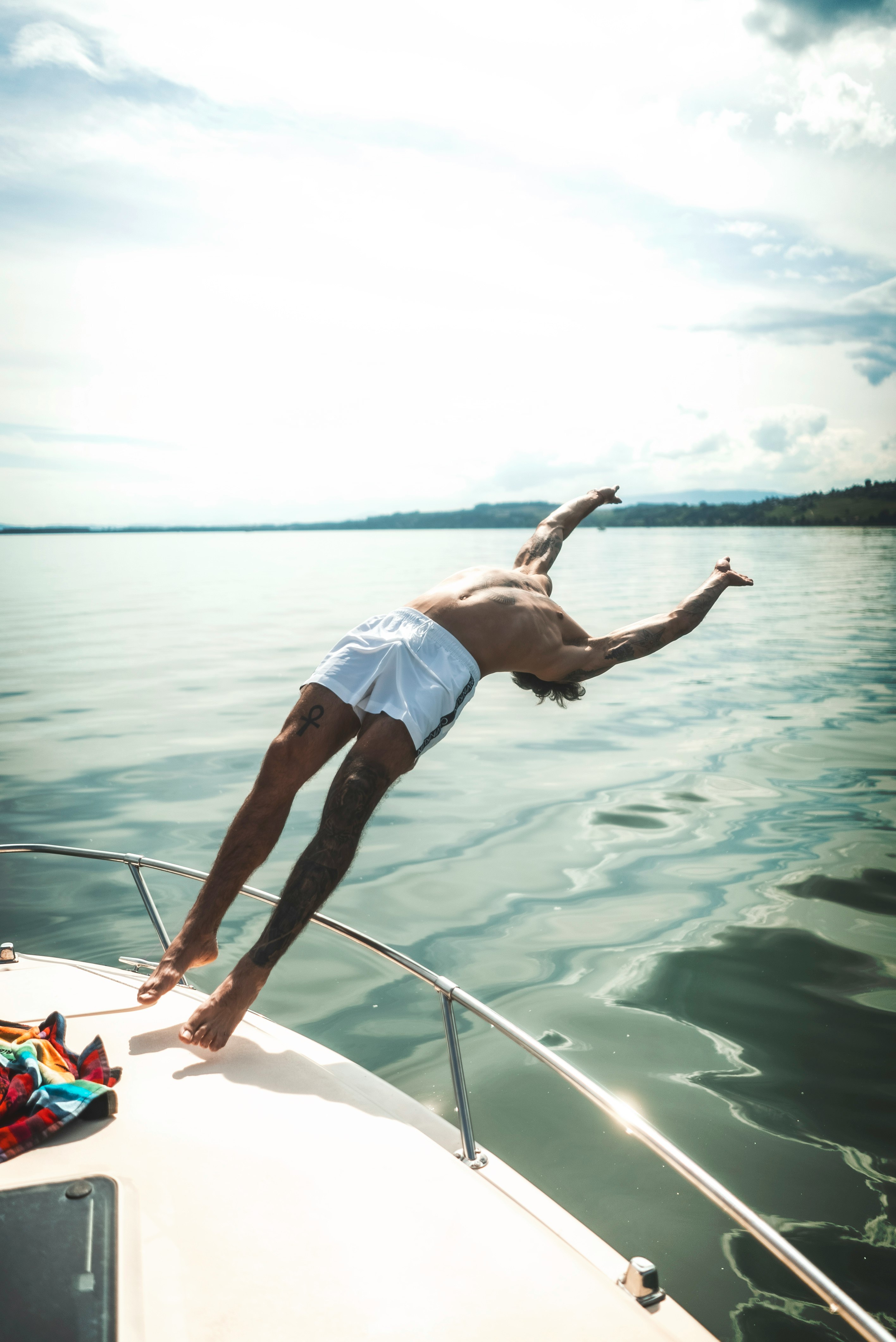 man in blue shorts jumping on white boat during daytime